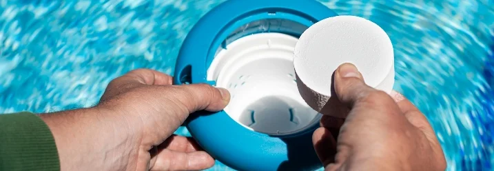 Hände legen Chlortablette in Dosierschwimmer